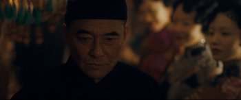 Movie still from “The Grandmaster” (2013), directed by Kar-Wai Wong – An older man wearing a black hat and looking at the camera; Close Up shot, Over the shoulder angle