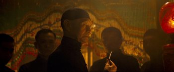 Movie still from “The Grandmaster” (2013), directed by Kar-Wai Wong – A man with a cigarette in his mouth and another man in the background; Close Up shot, Low angle