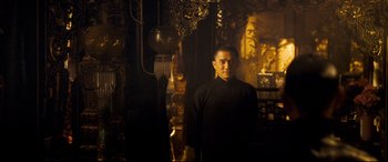 Movie still from “The Grandmaster” (2013), directed by Kar-Wai Wong – A man standing in a dark room in front of a chandelier; Medium shot, Low angle