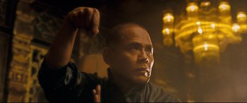 Movie still from “The Grandmaster” (2013), directed by Kar-Wai Wong – A bald man is holding his fist up in the dark; Close Up shot, Low angle