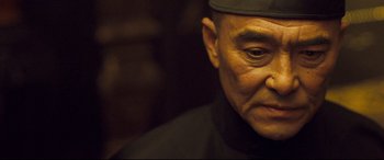 Movie still from “The Grandmaster” (2013), directed by Kar-Wai Wong – An older man wearing a black hat looking at the camera; Close Up shot, Low angle