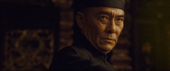 Movie still from “The Grandmaster” (2013), directed by Kar-Wai Wong – An older man wearing a black hat and a black jacket; Close Up shot, Low angle