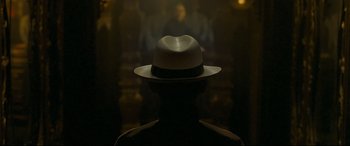 Movie still from “The Grandmaster” (2013), directed by Kar-Wai Wong – A man wearing a white hat in a dark room; Close Up shot, Over the shoulder angle