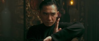 Movie still from “The Grandmaster” (2013), directed by Kar-Wai Wong – A man in a black shirt is holding his hand up to his face; Close Up shot, Over the shoulder angle
