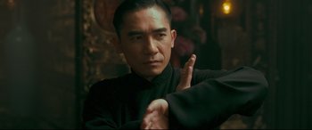 Movie still from “The Grandmaster” (2013), directed by Kar-Wai Wong – A man in a black shirt is doing a pose for the camera; Close Up shot, Over the shoulder angle