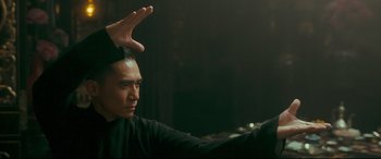Movie still from “The Grandmaster” (2013), directed by Kar-Wai Wong – A man in a black shirt is holding his hands up; Medium shot, Low angle