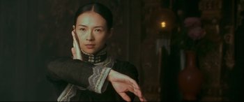 Movie still from “The Grandmaster” (2013), directed by Kar-Wai Wong – A woman in a black dress holding her hands up; Close Up shot, Over the shoulder angle