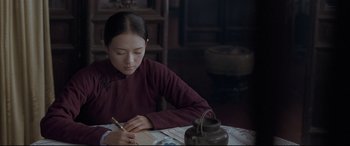 Movie still from “The Grandmaster” (2013), directed by Kar-Wai Wong – A young girl is writing on a piece of paper; Medium shot, Over the shoulder angle
