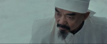 Movie still from “The Grandmaster” (2013), directed by Kar-Wai Wong – A man with a beard wearing a white hat; Close Up shot, Over the shoulder angle