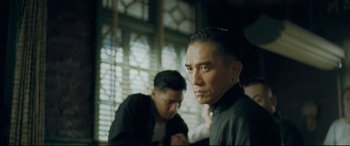 Movie still from “The Grandmaster” (2013), directed by Kar-Wai Wong – A man in a black shirt is looking at the camera; Medium shot, Over the shoulder angle