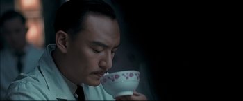 Movie still from “The Grandmaster” (2013), directed by Kar-Wai Wong – A man in a white shirt is drinking from a white cup; Close Up shot, Low angle
