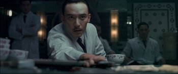 Movie still from “The Grandmaster” (2013), directed by Kar-Wai Wong – A man sitting at a table with a cup of coffee; Close Up shot, Low angle