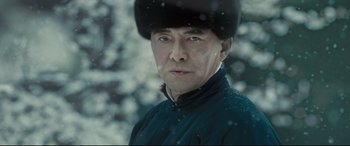 Movie still from “The Grandmaster” (2013), directed by Kar-Wai Wong – A man wearing a hat in the snow with trees in the background; Close Up shot, Low angle