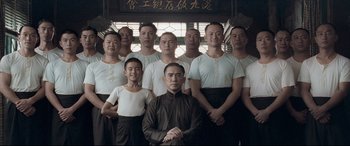 Movie still from “The Grandmaster” (2013), directed by Kar-Wai Wong – A group of men standing next to each other in front of a building; Medium shot, Low angle