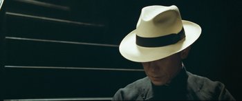 Movie still from “The Grandmaster” (2013), directed by Kar-Wai Wong – A man wearing a white hat sitting in front of a wall; Close Up shot, High angle
