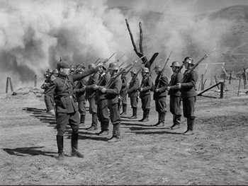 Movie still from “The Great Dictator” (1940), directed by Charles Chaplin – A black and white photo of a group of men in uniform holding guns; Wide shot, Low angle