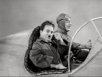 Movie still from “The Great Dictator” (1940), directed by Charles Chaplin – A man and a woman sitting in an airplane cockpit; Medium shot, Low angle