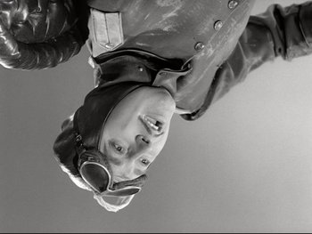 Movie still from “The Great Dictator” (1940), directed by Charles Chaplin – A man wearing a helmet and a leather jacket is hanging upside down; Medium shot, Low angle
