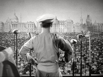Movie still from “The Great Dictator” (1940), directed by Charles Chaplin – An old photo of a man standing in front of a crowd; Wide shot, High angle