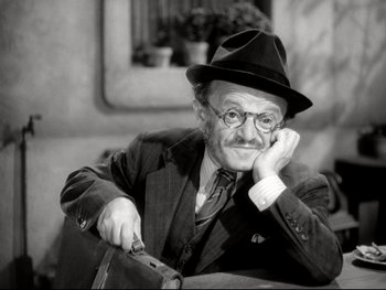 Movie still from “The Great Dictator” (1940), directed by Charles Chaplin – An older man in a suit and hat is holding a knife; Close Up shot, High angle