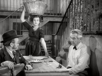 Movie still from “The Great Dictator” (1940), directed by Charles Chaplin – A woman standing at a table with a basket on top of her head; Medium shot, High angle