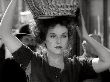 Movie still from “The Great Dictator” (1940), directed by Charles Chaplin – A black and white photo of a woman carrying a basket on top of her head; Medium shot, Low angle