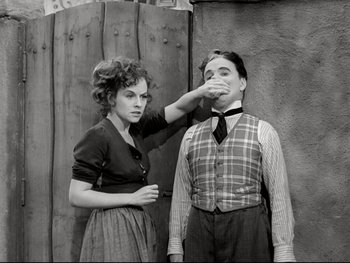 Movie still from “The Great Dictator” (1940), directed by Charles Chaplin – An old photo of a man and a woman standing next to each other; Medium shot, High angle