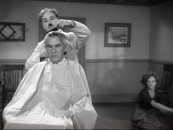 Movie still from “The Great Dictator” (1940), directed by Charles Chaplin – An older man getting his hair combed by an older woman; Medium shot, Over the shoulder angle