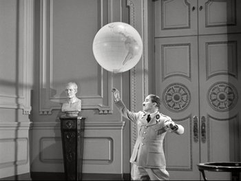 Movie still from “The Great Dictator” (1940), directed by Charles Chaplin – A black and white photo of a man holding an object in the air; Wide shot, Low angle
