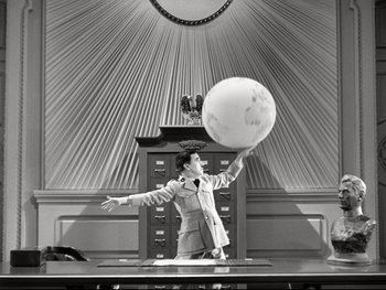Movie still from “The Great Dictator” (1940), directed by Charles Chaplin – A man in a suit and tie holding an object in the air; Medium shot, Low angle