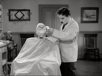 Movie still from “The Great Dictator” (1940), directed by Charles Chaplin – An old photo of a man getting his hair cut; Medium shot, Over the shoulder angle