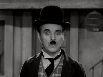 Movie still from “The Great Dictator” (1940), directed by Charles Chaplin – A person wearing a suit and a hat; Close Up shot, Low angle