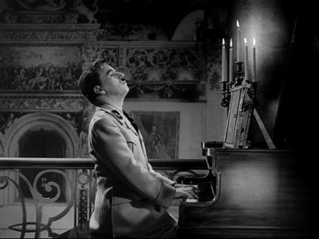 Movie still from “The Great Dictator” (1940), directed by Charles Chaplin – A man standing next to a grand piano in front of candles; Medium shot, Low angle