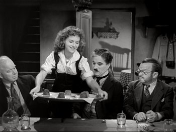 Movie still from “The Great Dictator” (1940), directed by Charles Chaplin – A woman is serving a tray of food at a party; Medium shot, High angle