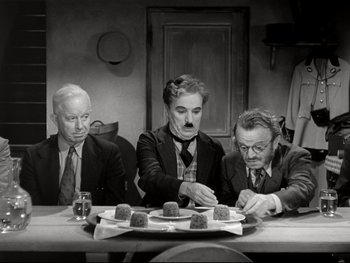Movie still from “The Great Dictator” (1940), directed by Charles Chaplin – A group of men sitting at a table with food; Medium shot, High angle