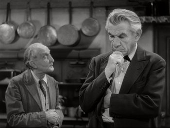Movie still from “The Great Dictator” (1940), directed by Charles Chaplin – Two men in suits and ties standing in a kitchen; Medium shot, Over the shoulder angle