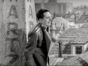 Movie still from “The Great Dictator” (1940), directed by Charles Chaplin – A man in a military uniform standing next to a building; Medium shot, Low angle