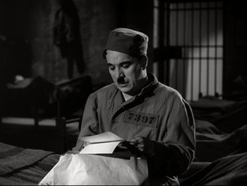 Movie still from “The Great Dictator” (1940), directed by Charles Chaplin – A man in a uniform is looking down at a bag; Medium shot, High angle