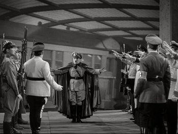 Movie still from “The Great Dictator” (1940), directed by Charles Chaplin – A man dressed as a nazi stands in front of a group of soldiers; Wide shot, High angle