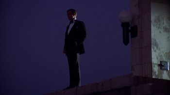 Movie still from “The Great Gatsby” (1974), directed by Jack Clayton – A man in a tuxedo standing on the side of a building; Wide shot, Low angle