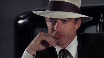 Movie still from “The Great Gatsby” (1974), directed by Jack Clayton – A person wearing a suit and a hat; Close Up shot, Low angle