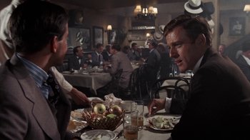 Movie still from “The Great Gatsby” (1974), directed by Jack Clayton – A group of people sitting at a table in a restaurant; Medium shot, Over the shoulder angle