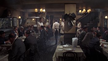 Movie still from “The Great Gatsby” (1974), directed by Jack Clayton – A group of people sitting at a table in a restaurant; Wide shot, High angle