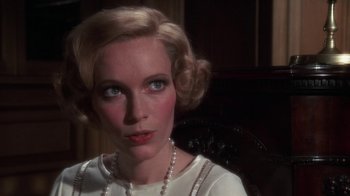 Movie still from “The Great Gatsby” (1974), directed by Jack Clayton – A woman in a white dress with a pearl necklace; Close Up shot, Over the shoulder angle