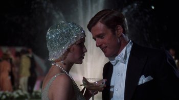 Movie still from “The Great Gatsby” (1974), directed by Jack Clayton – A man and a woman holding a glass of champagne; Close Up shot, Low angle