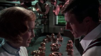 Movie still from “The Great Gatsby” (1974), directed by Jack Clayton – A man and a woman looking at each other in front of copper pans; Close Up shot, Over the shoulder angle