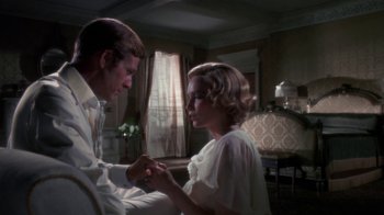 Movie still from “The Great Gatsby” (1974), directed by Jack Clayton – A man and a woman holding hands in a living room; Medium shot, Over the shoulder angle