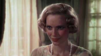 Movie still from “The Great Gatsby” (1974), directed by Jack Clayton – A woman wearing a white dress and a pearl necklace; Close Up shot, Over the shoulder angle
