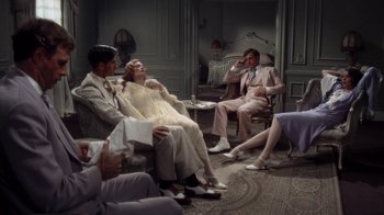 Movie still from “The Great Gatsby” (1974), directed by Jack Clayton – A group of people sitting in a living room together; Wide shot, High angle