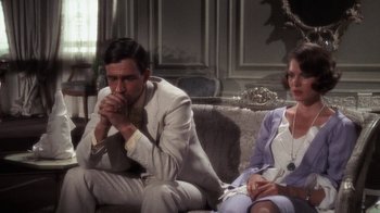 Movie still from “The Great Gatsby” (1974), directed by Jack Clayton – A man and a woman sitting on a couch; Medium shot, High angle